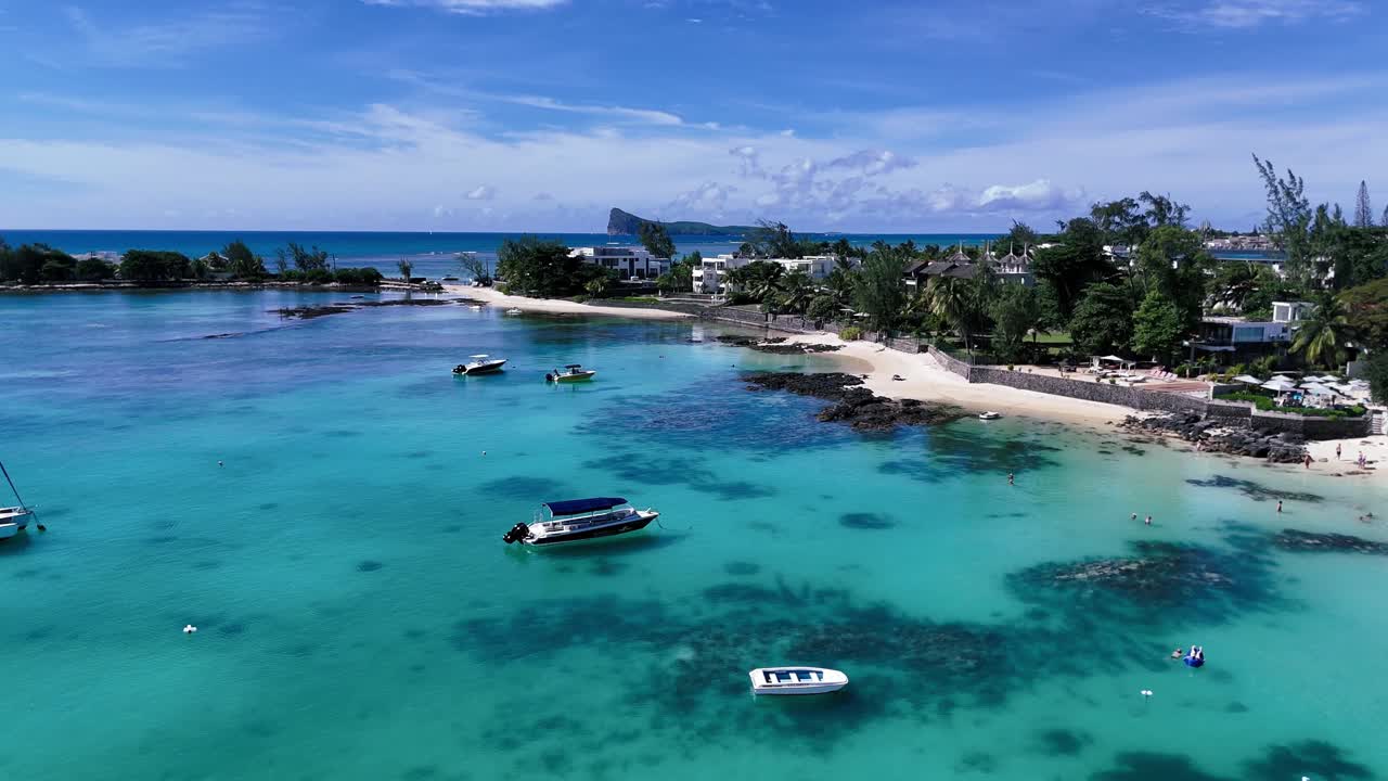 Crystal-clear aerial view of Pereybere Beach, Mauritius, with turquoise waters, anchored boats, white sand, and tropical trees under vibrant blue skies, perfect island paradise.