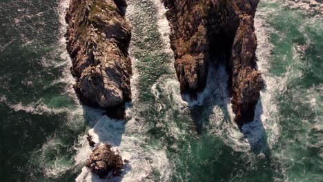 Vista-Superior-Aérea-De-Las-Olas-Rompiendo-En-Las-Rocas-En-Un-Océano-Azul