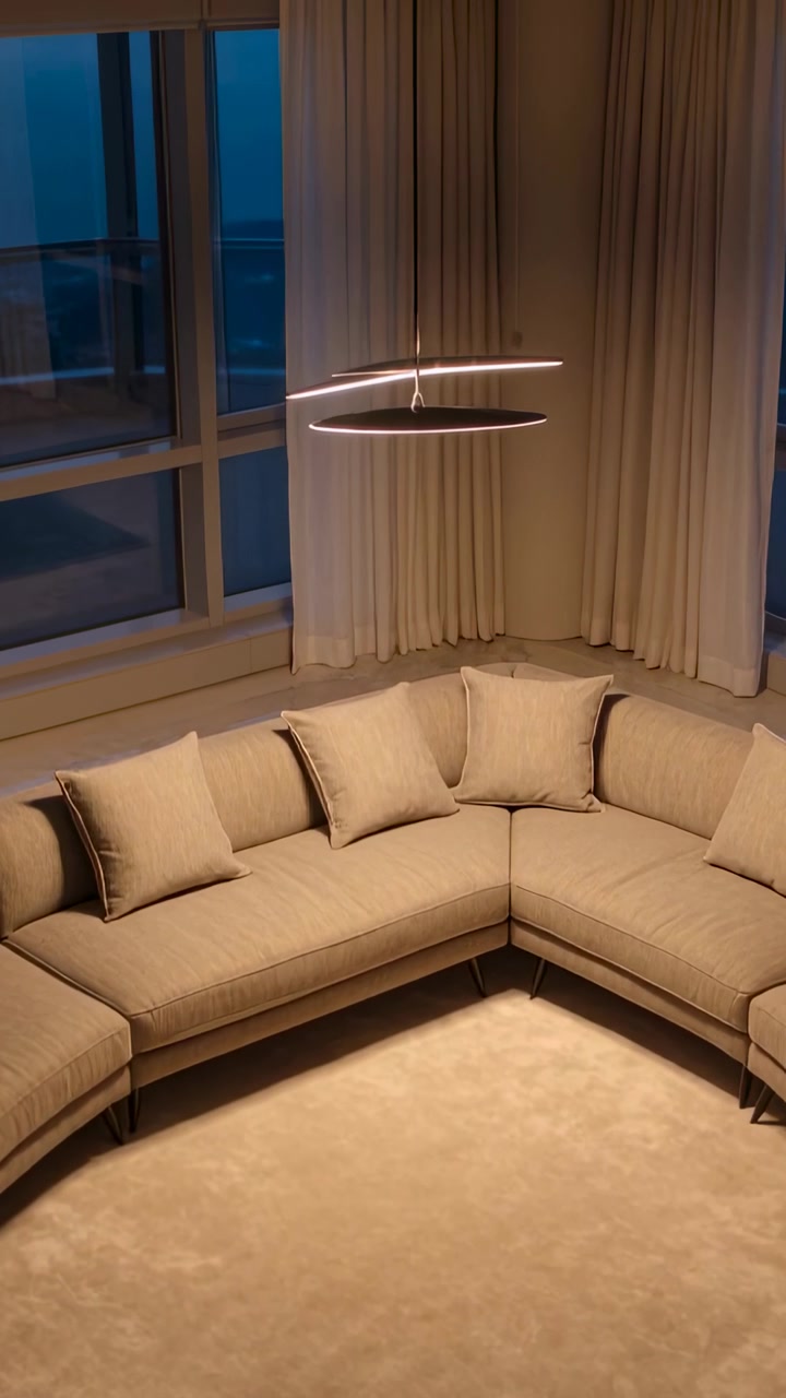 Vertical video: Tilting camera revealing curved sofa at home corner, pendant rotating above pillows