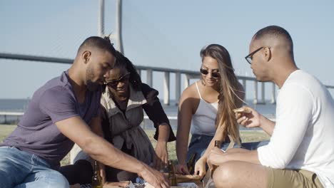 Smiling-friends-eating-pizza-during-picnic.