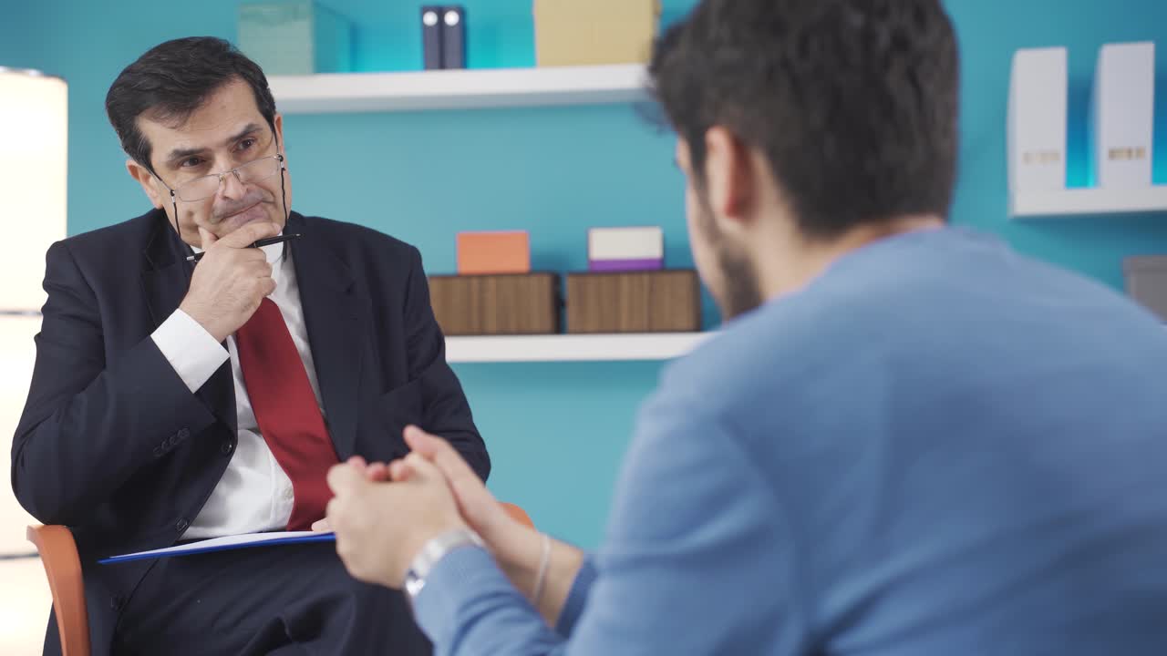un psicólogo maduro escuchando a un paciente joven, haciendo un diagnóstico.