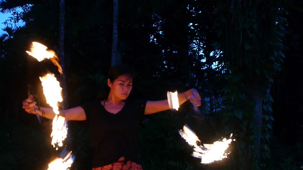 Asian woman performing fire dance with spinning fire fans