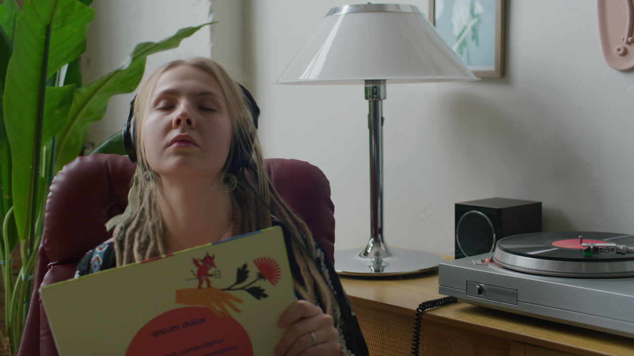 Woman in Headphones Holding Vinyl Record and Enjoying Music on Turntable
