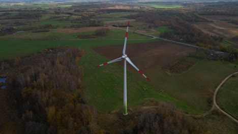 Toma-Aérea-De-Un-Molino-De-Viento-Giratorio-Con-Bordes-Rojos-Para-La-Producción-De-Energía-Eléctrica-Renovable-En-Un-Campo