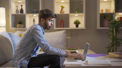 hombre riendo usando una computadora portátil por la noche.