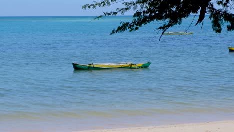 solo traditional timorese green and yellow wooden fishermen's fishing canoe boat on remote tropical island timor leste, south east asia