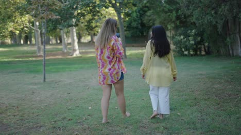 two women walking barefoot in a park
