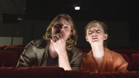 Front-View-Of-Concentrated-Couple-Sitting-In-The-Cinema-While-They-Watching-A-Movie