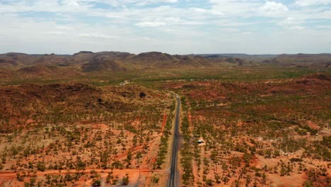 panorama of the long asphalt road amidst the grassland with a view of the mountains in northern territory of australia