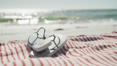 close up of flip flops and towel on beach, in slow motion, with copy space