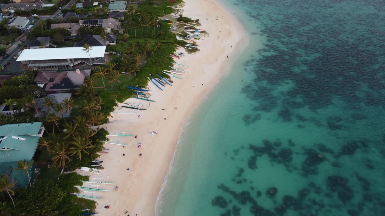 Ripresa cinematografica 4K con drone in senso antiorario di canoe a bilanciere sulla spiaggia di Lanikai durante l'alba a Oahu
