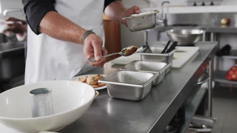 cocinero caucásico derramando salsa en un recipiente en el mostrador en la cocina, en cámara lenta