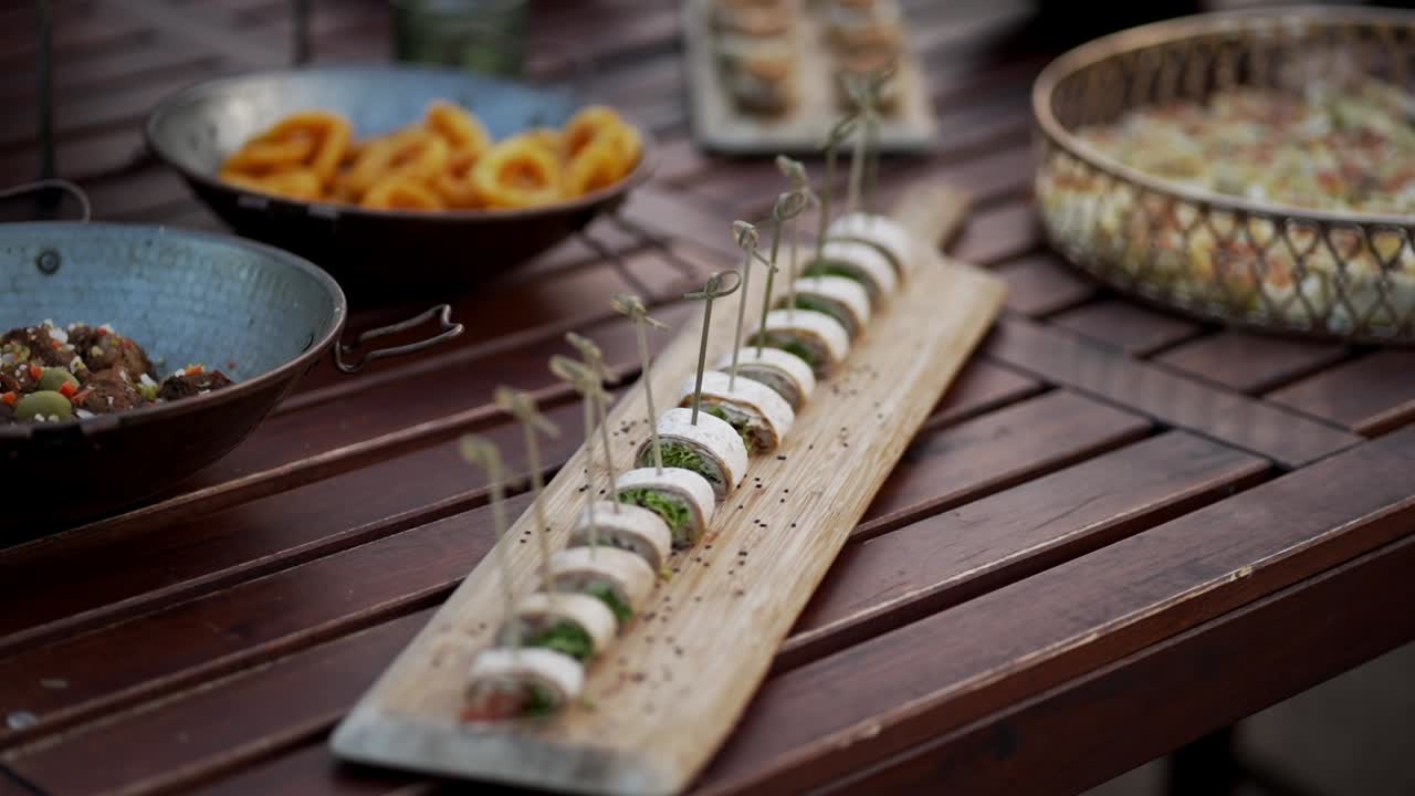 Gourmet skewers of cheese and herbs displayed on a wooden board with other party snacks