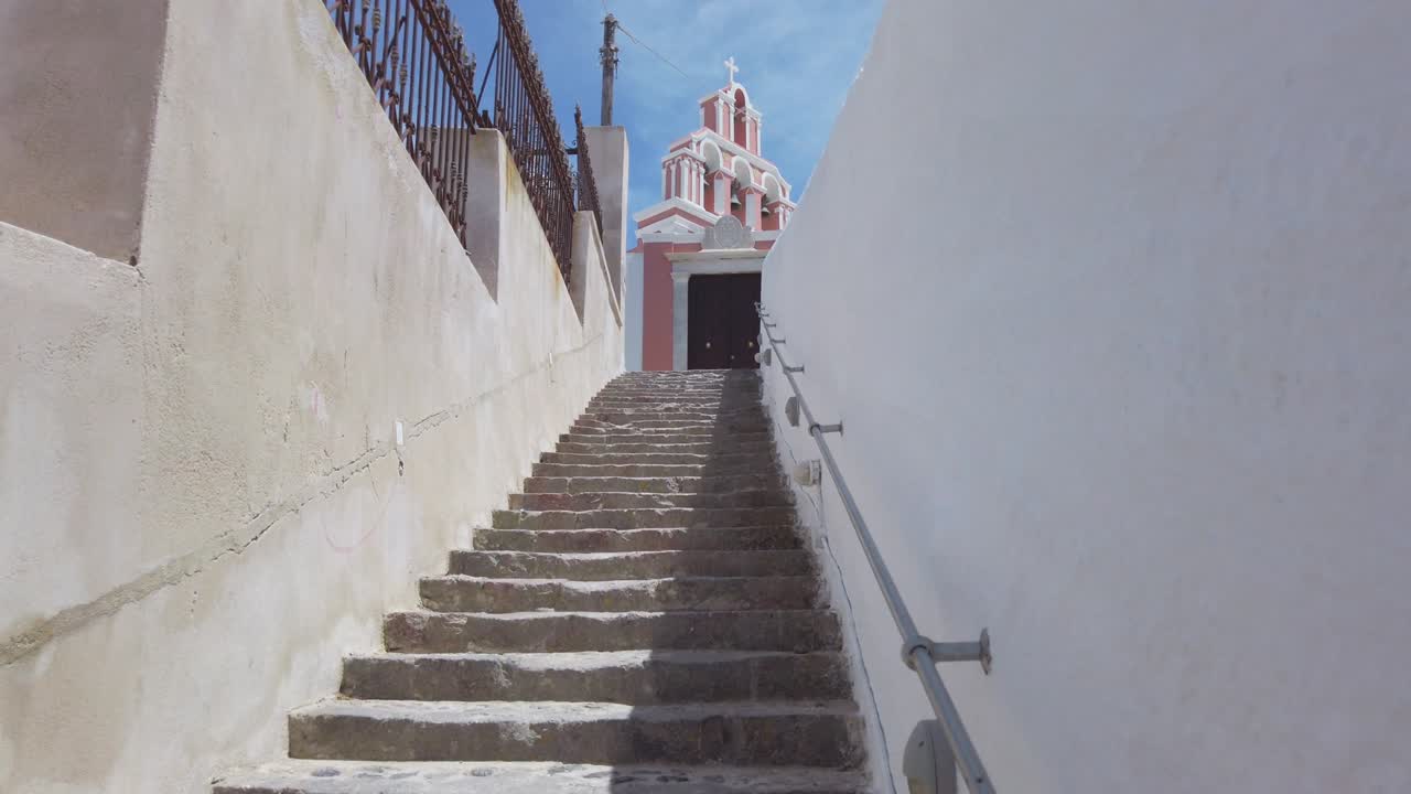 mujer con sombrero camina por las escaleras de la torre del campanario del monasterio católico de monjas dominicas en la ciudad de fira en santorini, cámara lenta