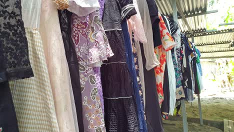 a rack of secondhand clothes and dresses displayed on a market stall at second-hand clothing markets in southeast asia