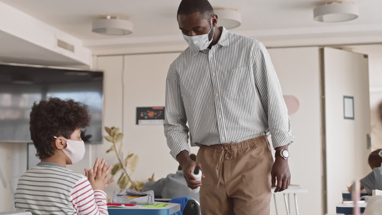 Teacher Disinfecting Kids Hands in Class