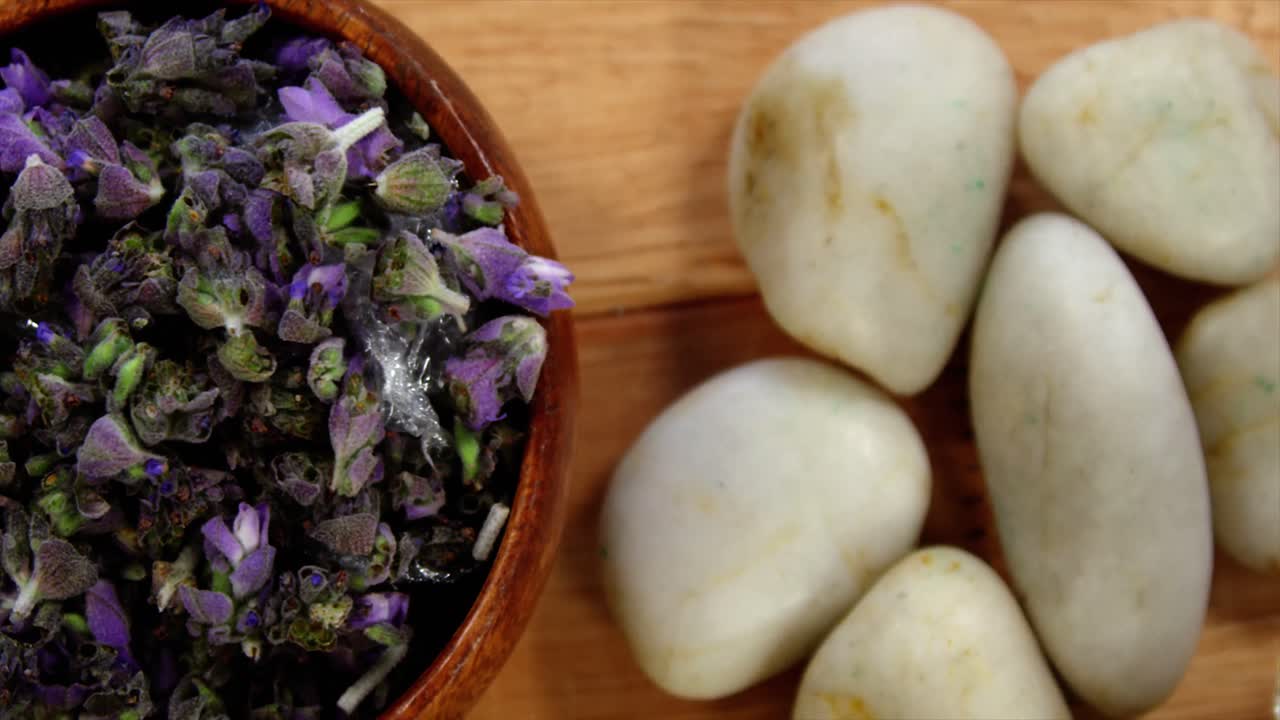 cuenco de madera con pétalos de lavanda y piedra de guijarros