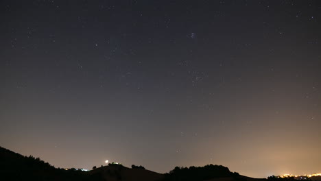 starry night to sunrise sky time-lapse with some clouds, above hills and nature