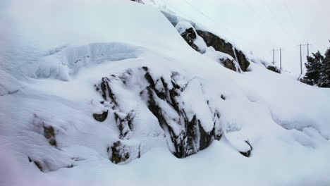 Zwischen-Schneebedeckten-Felsen-Und-Bäumen-Liegen-In-Der-Ferne-Stromleitungen