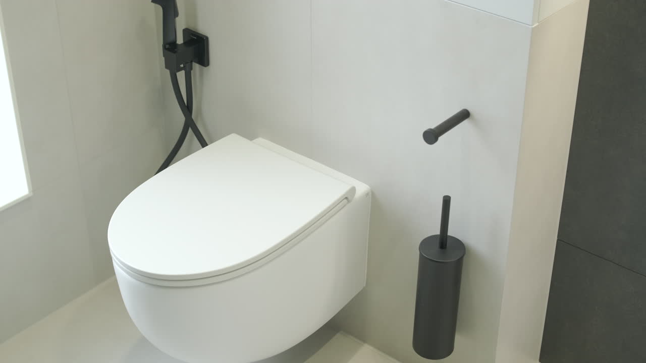 Vaso WC moderno bianco con doccetta bidet nera e accessori in un bagno pulito