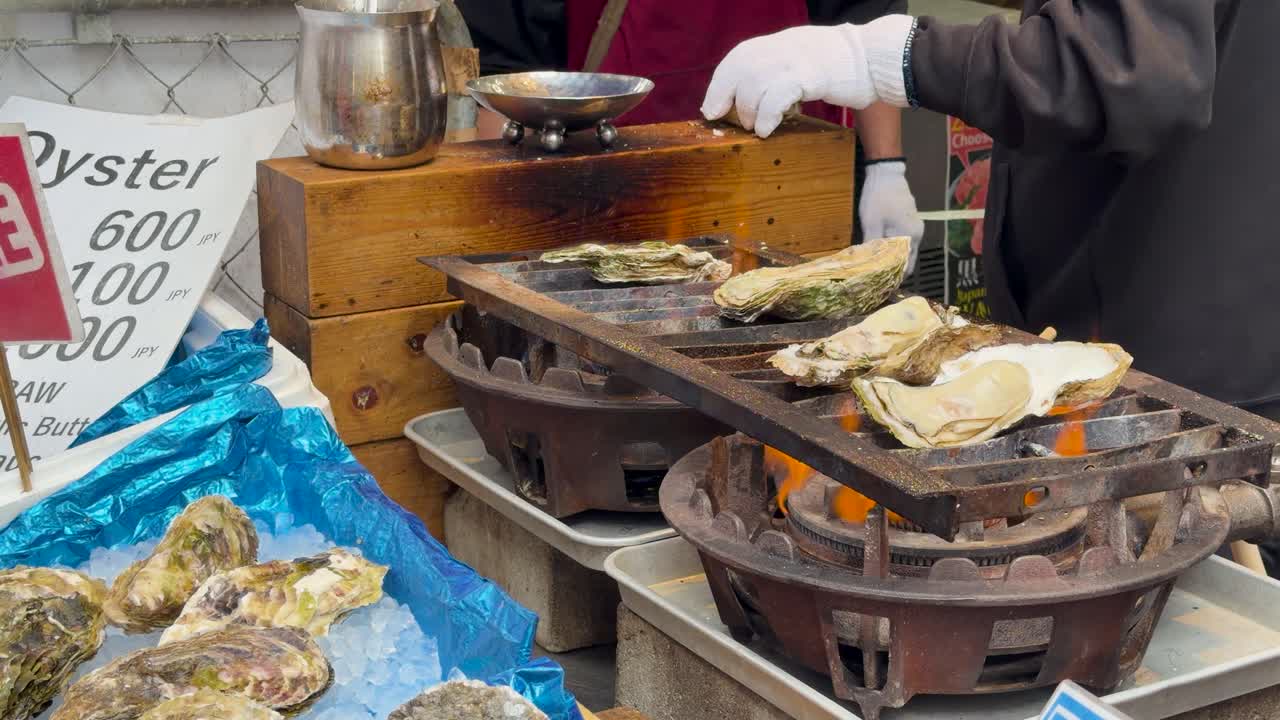 Un venditore ambulante di cibo griglia ostriche giganti su braci ardenti a Tokyo, Giappone
