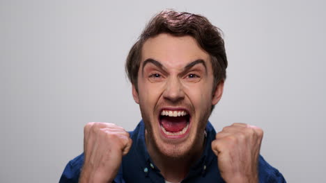 angry guy screaming in studio. rage model shouting on light background