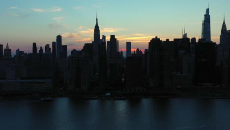 dramatic aerial rise and tilt towards the legendary midtown manhattan skyline at dusk