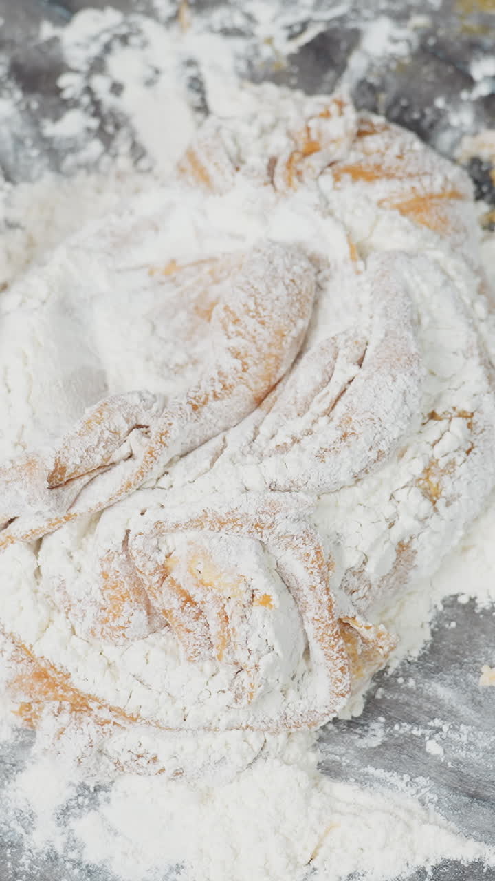 가루로 된 타일 테이블에서 반죽이 여있는 위에서 아래로 보이는 모습, 손으로 압축하고 접는 동안 표면에 어져있는 밀가루가 기 위해 준비되는 부드러운 반죽