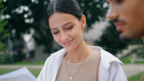 chica sonriente mirando papeles en el parque de cerca. estudiantes universitarios aprendiendo juntos