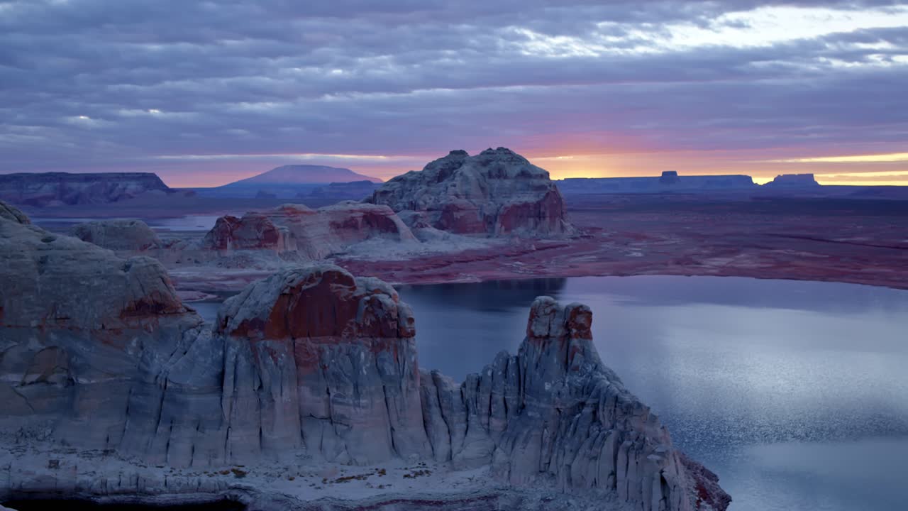 A breathtaking drone shot sweeps around Glen Canyon, showcasing its intricately eroded cliffs and Lake Powell’s vast waters.