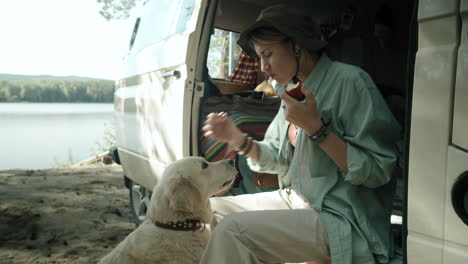 woman eating apple and petting dog in camper van