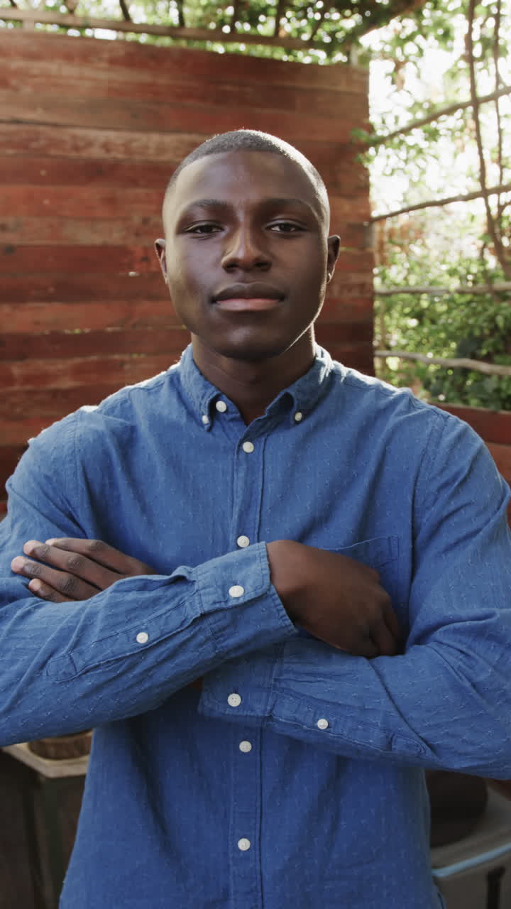 Vertical video of portrait of african american man crossing arms at coffee shop, slow motion