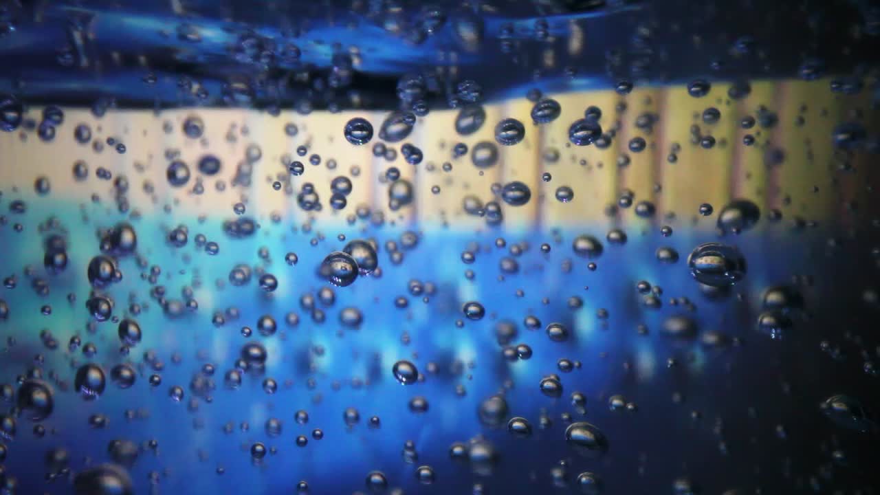 손 소독제의 큰 병 매크로, 배경은 화려합니다 - 병 아래의 조명은 공기 방울을 강조하기 위해 색상을 변경합니다