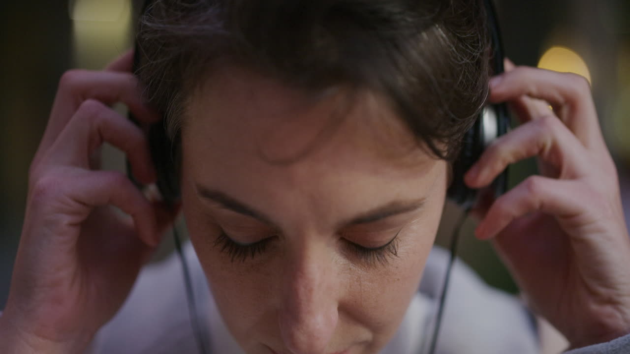 retrato de cerca mujer joven atractiva escuchando música se quita los auriculares mirando feliz a la cámara en cámara lenta