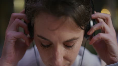 close up portrait attractive young woman listening to music takes off headphones looking happy at camera slow motion