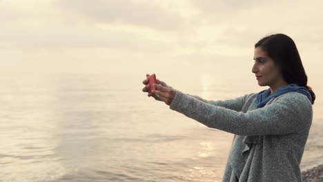 mujer tomando una selfie en la playa al atardecer