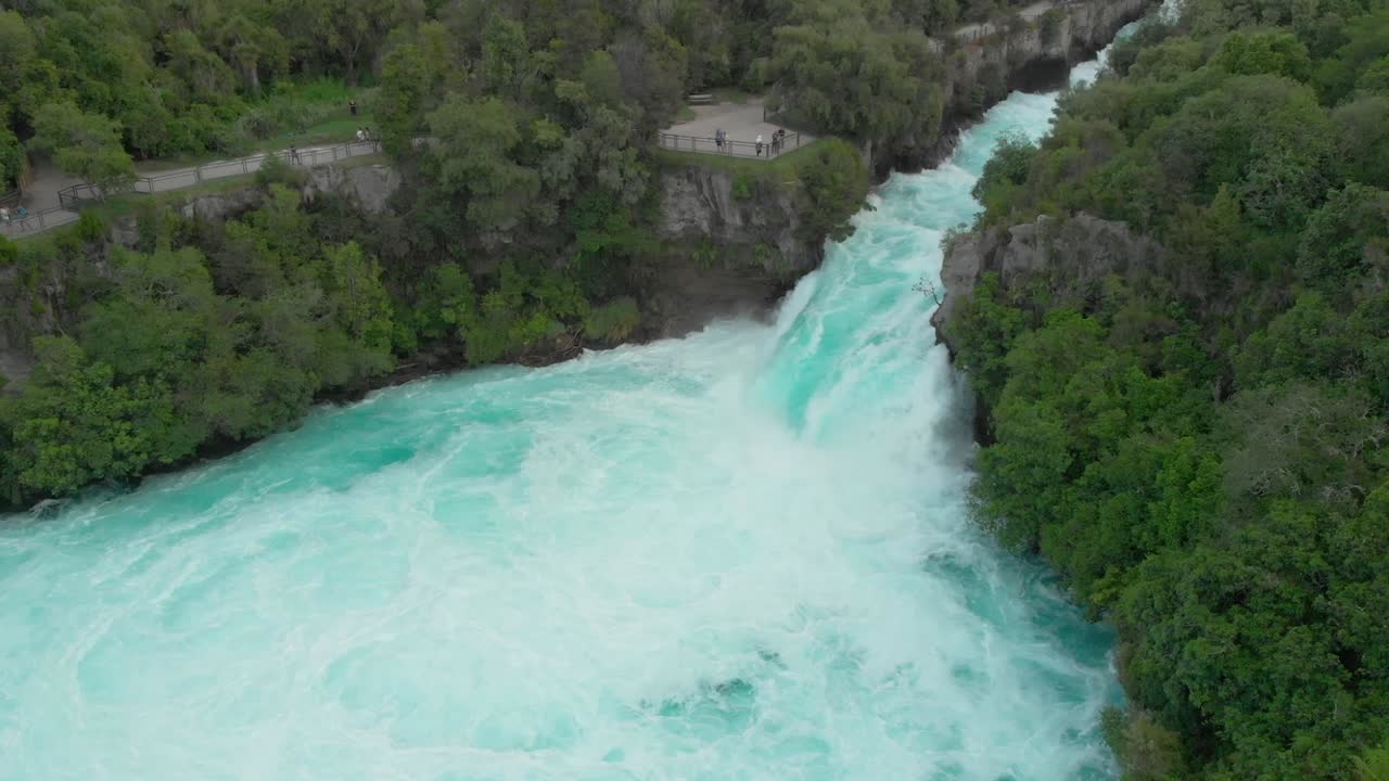SLOWMO - Aerial drone shot of spectacular waterfall Hukas Falls and tourists at viewpoint, New Zealand