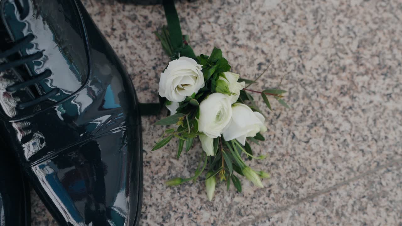 Scarpe da sposa eleganti abbinate a un fiore all'occhiello fresco su pavimento in granito