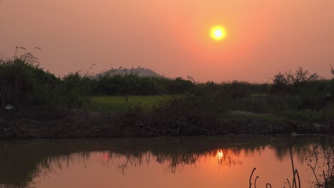 Orangefarbene-Sonne-Bei-Sonnenuntergang-über-Dem-Wasser-Auf-Dem-Land-In-Der-Abenddämmerung