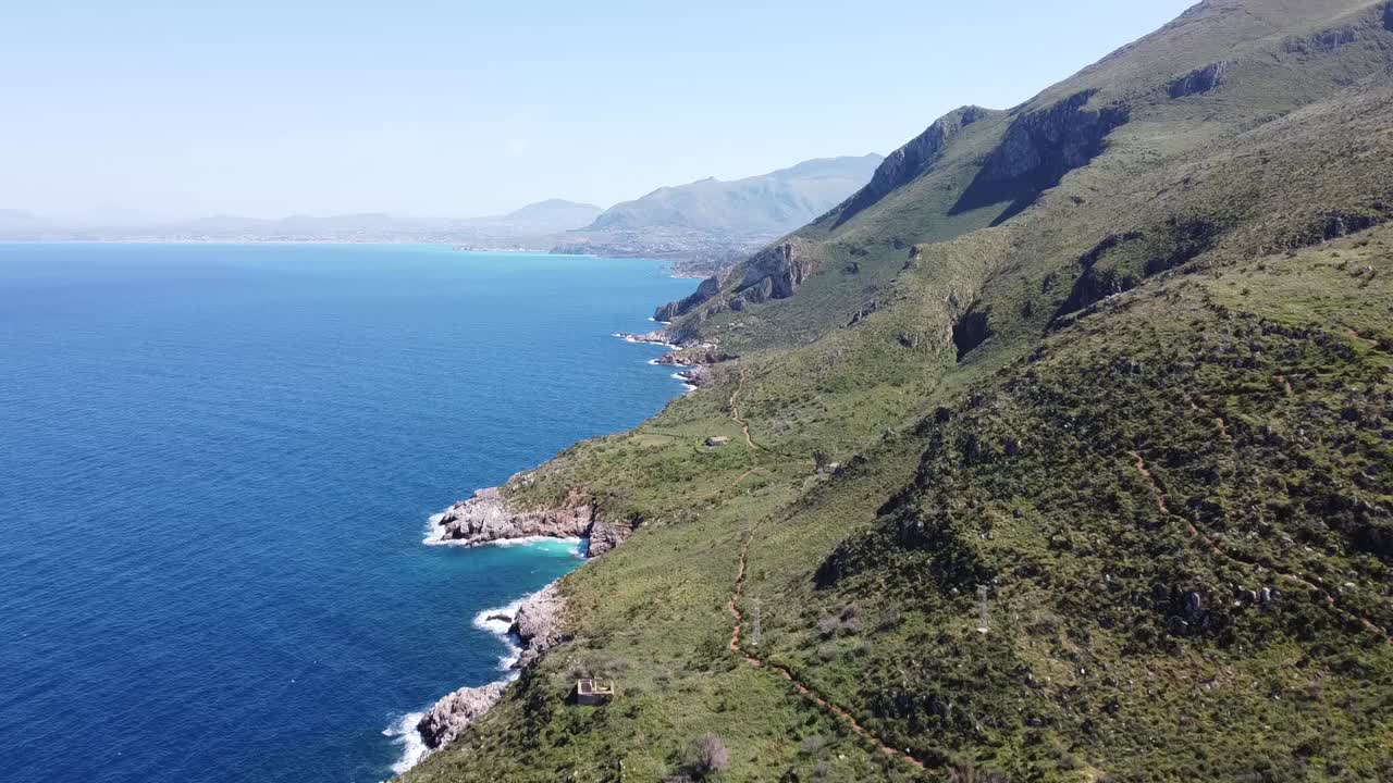 vuelo desde zingaro hacia el oeste en la costa norte de la isla de sicilia en italia, exuberantes colinas verdes con mar azul profundo, buen clima