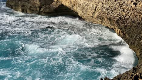 choppy sea splashing against eroded limestone rock face, san lawrenz, gozo