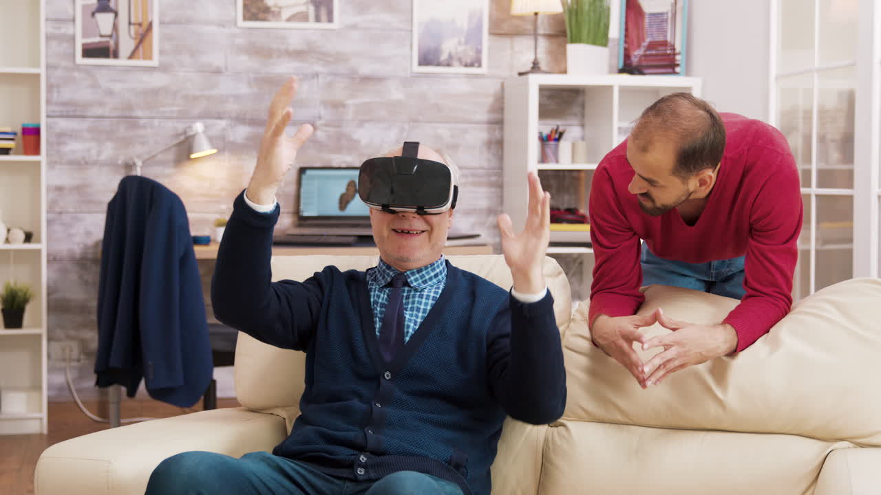 Senior man using virtual reality headset with his son at home