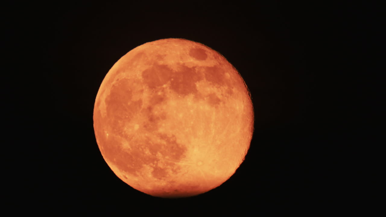 Large full moon rising against a dark night sky with clear details and dramatic atmosphere