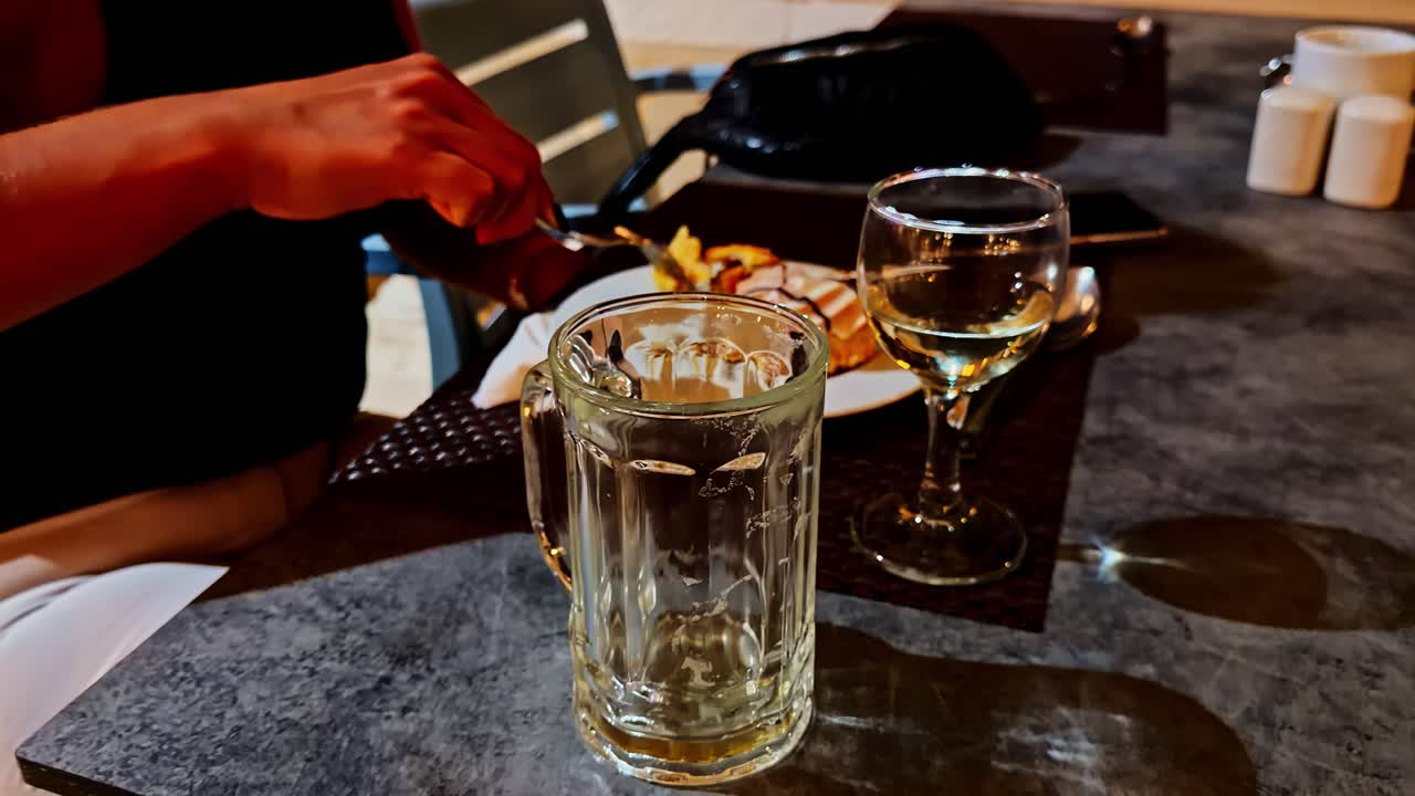 Cafébord om aftenen med vin, isdrik og dessert under varmt lys, der skaber en hyggelig stemning af natteliv
