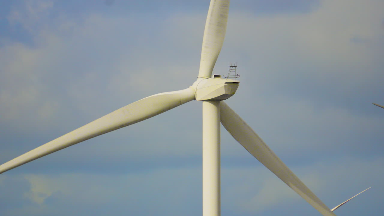 Solo Wind Turbine Spinning Creating Electricity with Clouds and Blue Sky in Background. Eco-Friendly Energy Generation