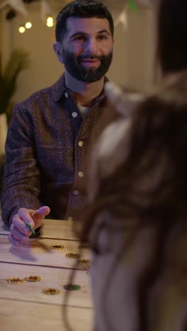 Vertical-Video-Of-Friends-At-Home-Or-In-Bar-Celebrating-At-St-Patrick's-Day-Party-Playing-With-Novelty-Gold-Coins