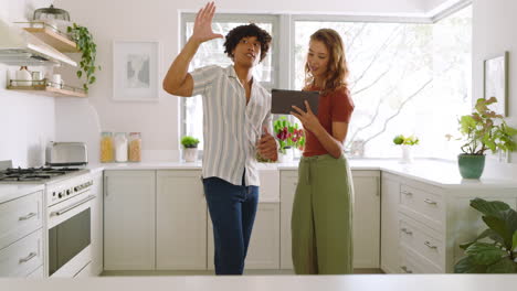 diverse couple in kitchen using tablet, discussing recipe with focused expressions, at home