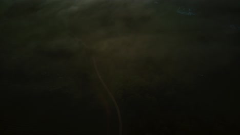 tiro de dron de la carretera y la inclinación hacia las montañas y las nubes bajas más allá