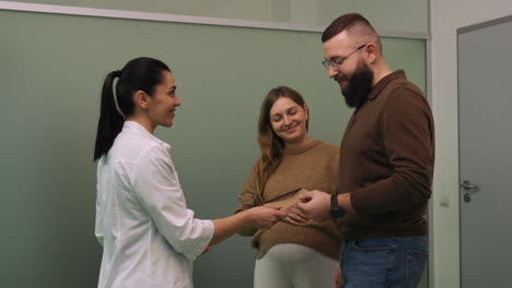 el doctor le da un sobre a una pareja.