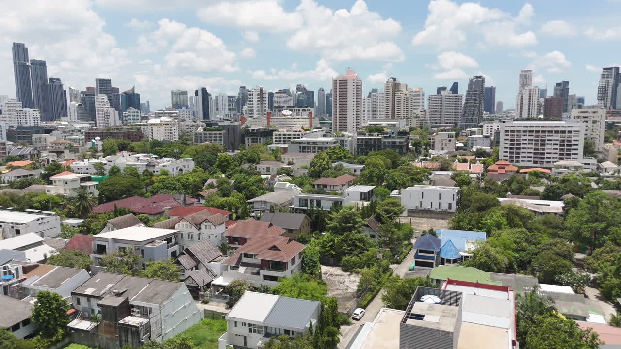 Contrasting Bangkok: quiet homes and trees set against soaring skyscrapers.